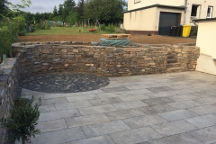 Natursteinmauer mit Terrasse links